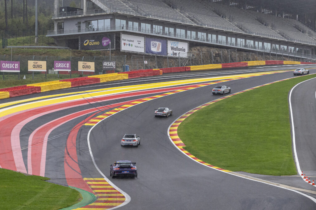 Groupe de voitures de sport en session de coaching Discovery sur la piste humide de Spa-Francorchamps.