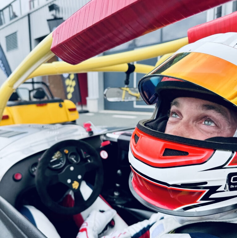 Pilote équipé d'un casque intégral et d'un système de sécurité dans le cockpit d'une voiture de sport lors d'un premier trackday à Mettet.
